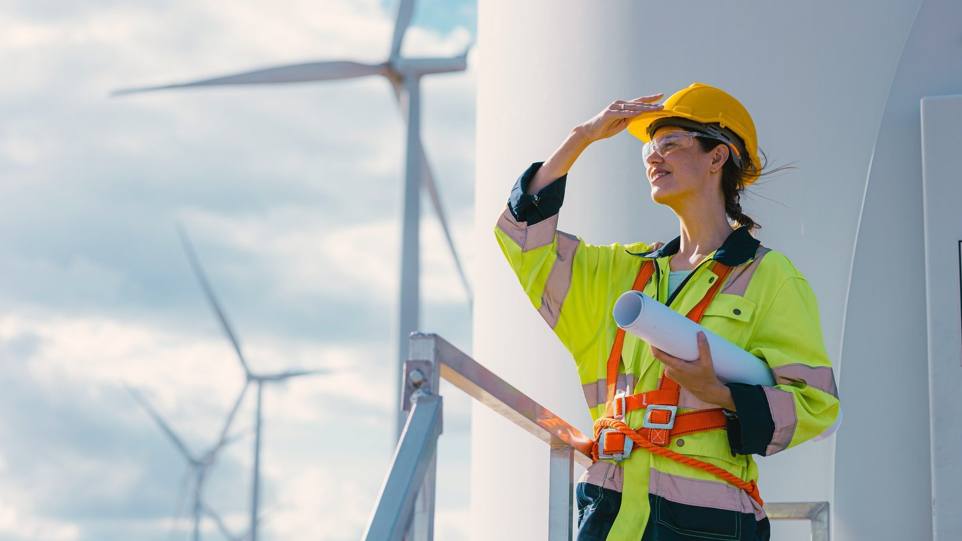 Frau in Sicherheitskleidung vor Windkraftanlagen.