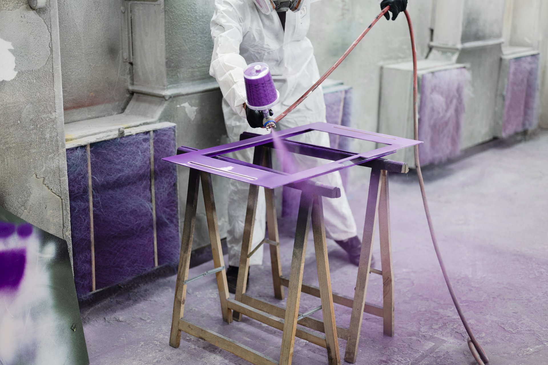 Eine Person sprüht lila Farbe auf die Bauelemente der Erzählbox.