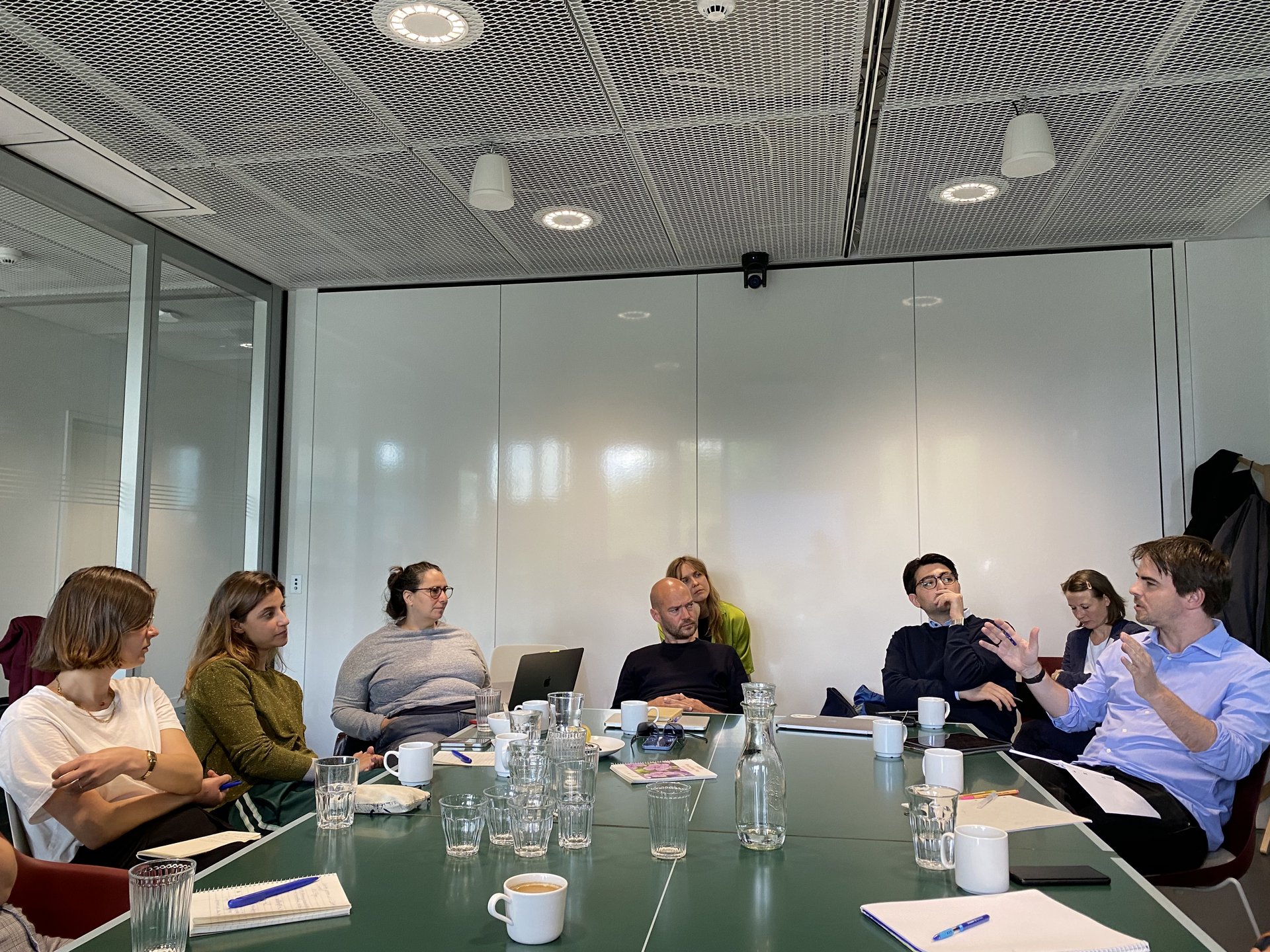 Eine Gruppe Menschen an einem Konferenztisch diskutiert.