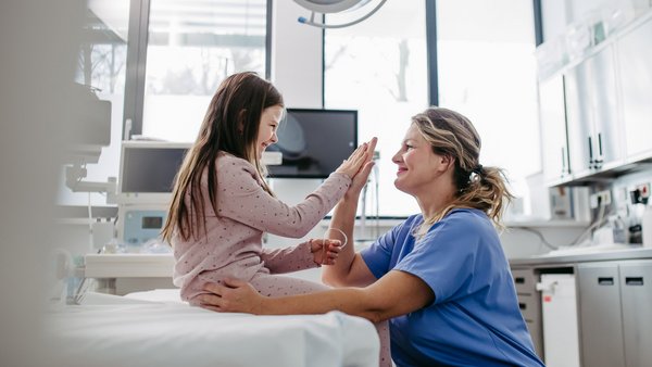 WJ26_Frauengesundheit_Kindergesundheit Eine Äzrtin und ein Mädchen klatschen in einem Behandlungszimmer ab.