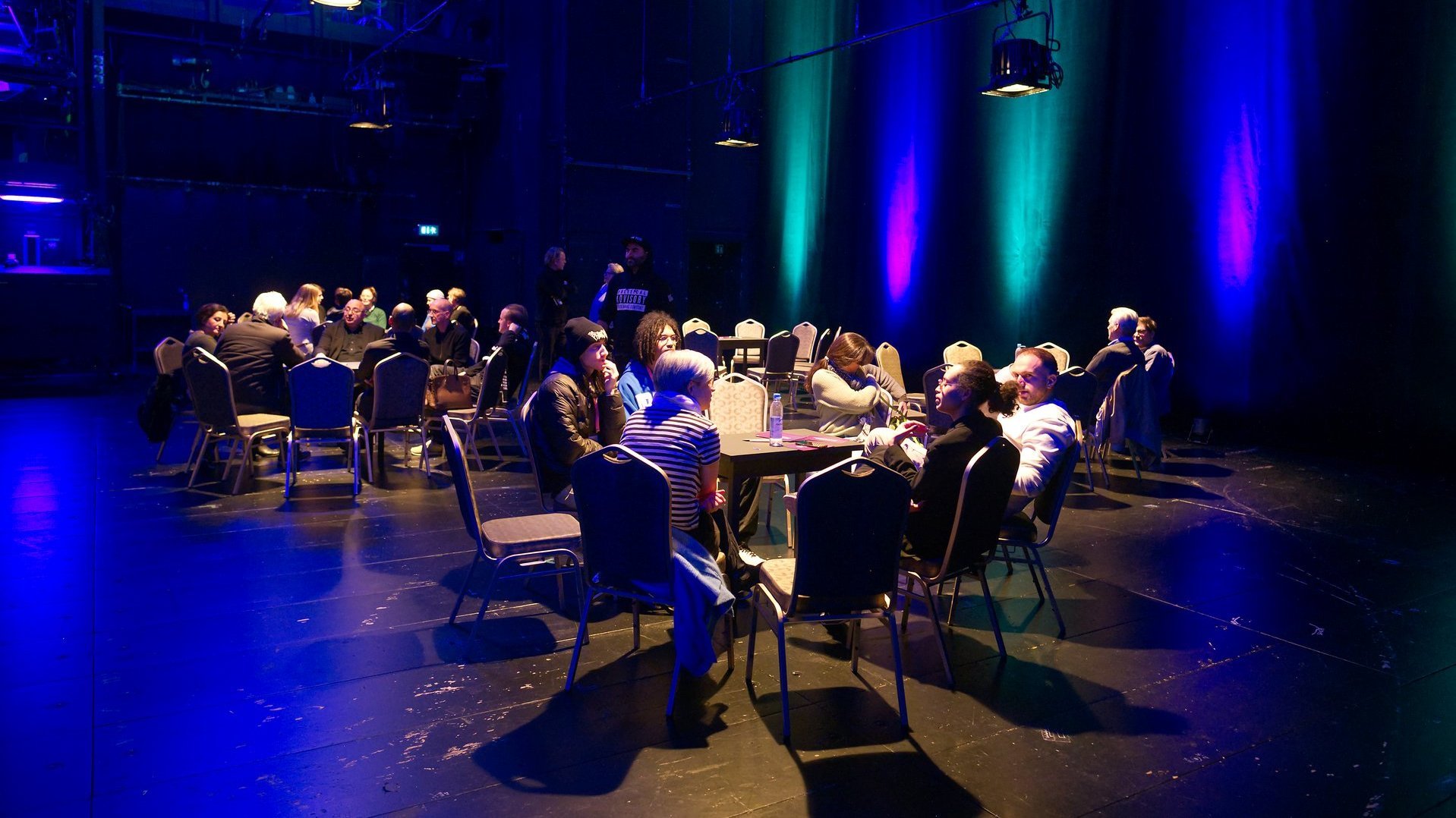 Mehrere Tischgruppen auf der Bühne im Gespräch.