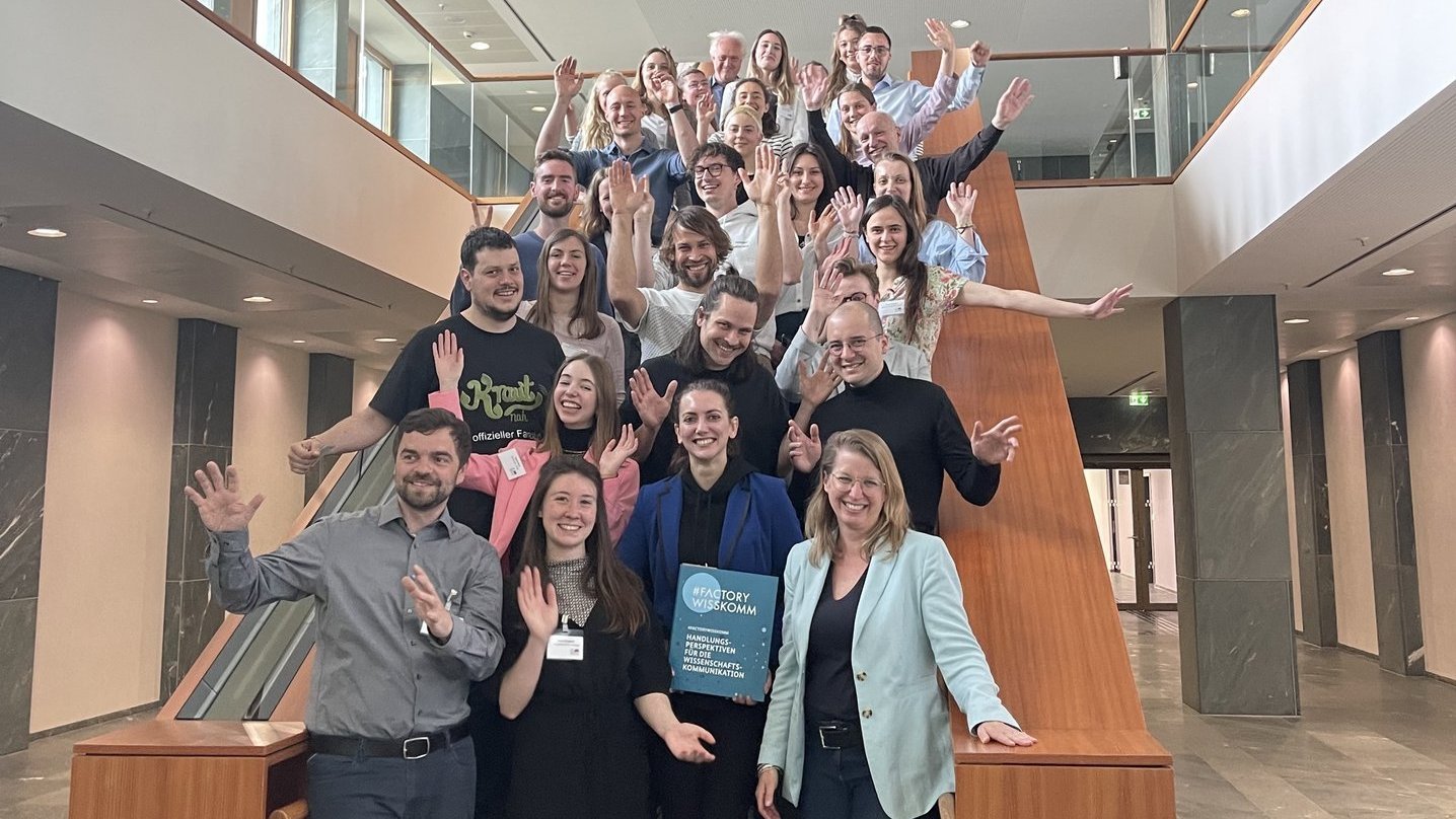 Eine Gruppe junger Menschen steht auf einer Treppe und winkt.