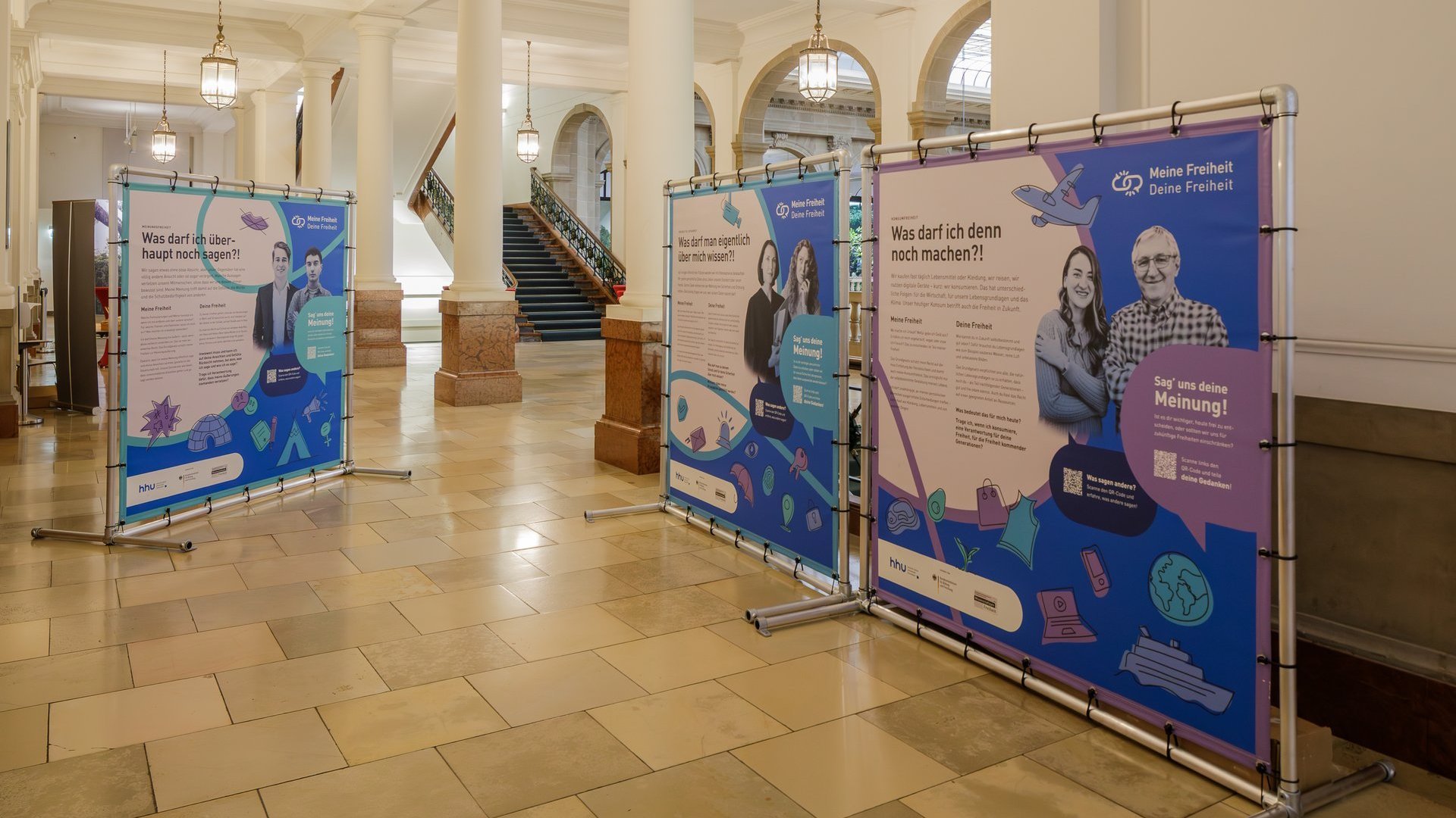 Große Plakatwände in einem Universitätsflur.