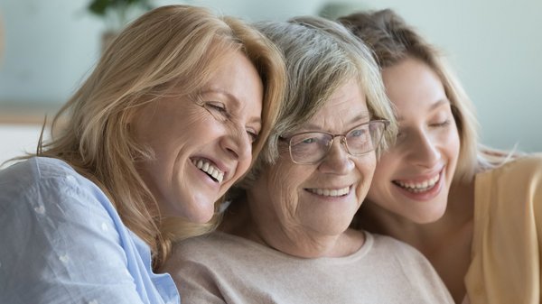 WJ26_Frauengesundheit_Altersgruppen Drei Frauen in verschiedenem Alter sitzen zusammen und lachen.